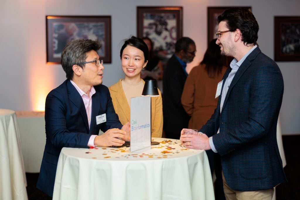 2 men and a woman standing at a high-top table talking